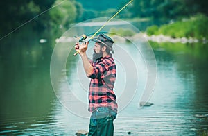 Young man fishing. Fisherman with rod, spinning reel on river bank. Man catching fish, pulling rod while fishing on lake