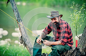 Young man fishing. Fisherman with rod, spinning reel on river bank. Man catching fish, pulling rod while fishing on lake