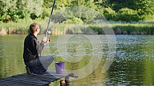 A young man is fishing in a pond