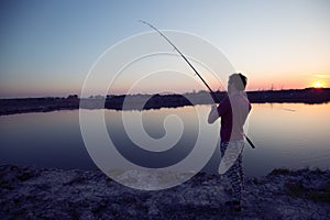 Young man fishing at pond and enjoying hobby