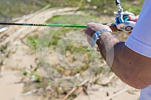 Young man fishing in pond, lake, closeup of fishing rod and reel