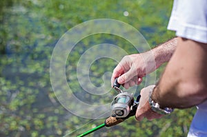 Young man fishing in pond, lake, closeup of fishing rod and reel