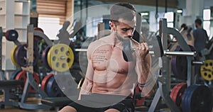 Young man with a fit body practicing sport on the gym working in his biceps lifting up the weights