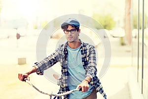 Young man with fixed gear bicycle walking in city