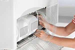 Young man fixing air conditioner at home