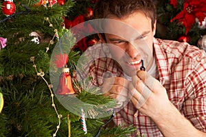 Young man fixing christmas tree lights at home