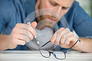young man fixing glasses with bending pliers