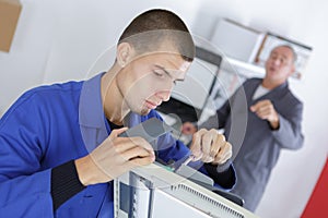 Young man fixing printing machine