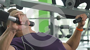 Young man flexing chest muscles on gym machine