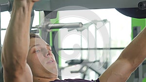 Young man flexing chest muscles on gym machine