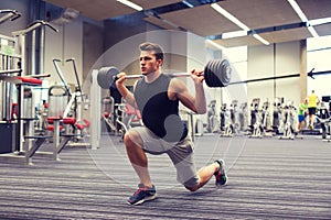 Young man flexing muscles with barbell in gym