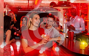 Young man flirting with women bar counter and drinking cocktails