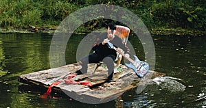 Young man floating on a raft. He`s rowing an electric guitar.