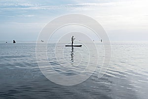 Young man floating on stand up paddle board on the sea on sunny summer day, active lifestyle, outdoor activity