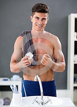 Young man flossing his teeth in front of mirror