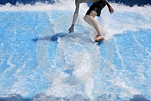 Young man flowriding and flowboarding on artificial sheet waves