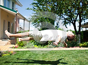 Young man flying or levitating over grass