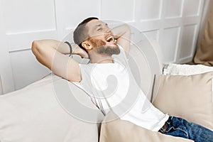 young man folded his hands and laughs while sitting on the couch at home