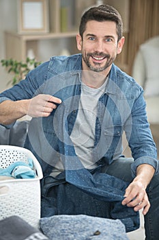 young man folding laundry on sofa