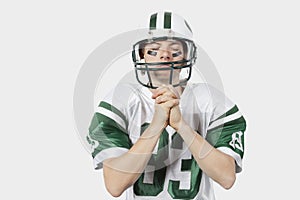 Young man in football uniform praying before game