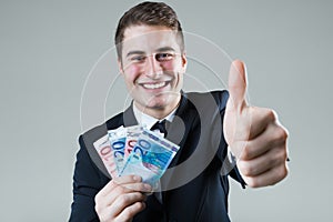 Young man in formalwear holding money.