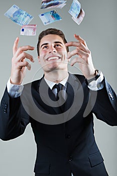 Young man in formalwear throwing money.