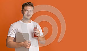 Young man freelancer holding laptop and drinking red healthy detox smoothie