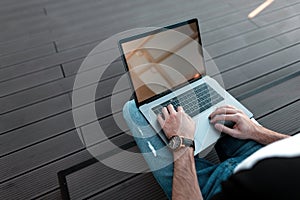 Young man freelancer working. Men`s hands and a modern metal laptop. Working time. View from above.