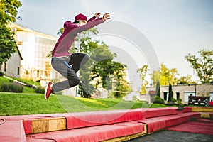 Young man freerun in summer city public park running, jumping and flying, parkour concept