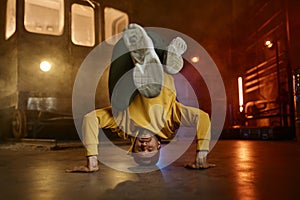 Young man freestyle dancer standing on head doing acrobatic stunt