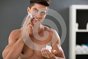 Young man front of mirror with shave foam on hand