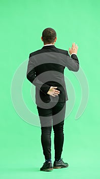 young man in full growth. isolated on green background. view from the back