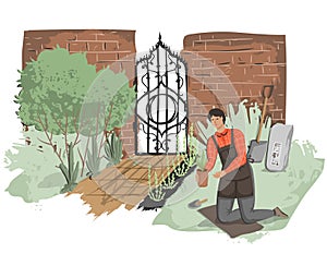 Young man gardener working outdoor. Old garden with brick fence and forged door.