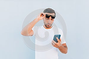 Young man gasping, shocked and appalled by a message he receives on blue background