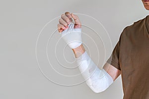 Young man with gauze bandage wrapped around his injured arm at home. Man with hand wrapped in medical bandage on white background