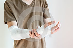 Young man with gauze bandage wrapped around his injured arms, knee at home. Man with hands wrap in medical bandage on white