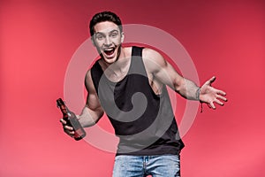 Young man gesturing with beer bottle and smiling at camera