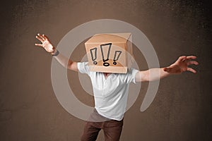 Young man gesturing with a cardboard box on his head with exclamation point