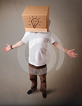 Young man gesturing with a cardboard box on his head with light bulb