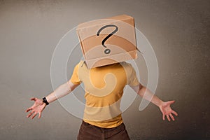 Young man gesturing with a cardboard box on his head with question mark photo