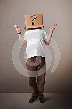 Young man gesturing with a cardboard box on his head with question mark