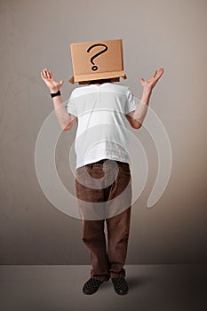 Young man gesturing with a cardboard box on his head with question mark photo