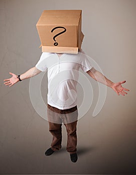 Young man gesturing with a cardboard box on his head with question mark