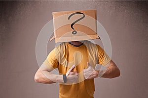 Young man gesturing with a cardboard box on his head with question mark