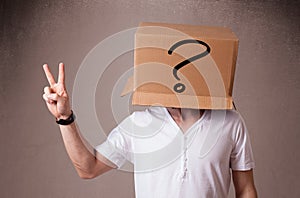 Young man gesturing with a cardboard box on his head with question mark