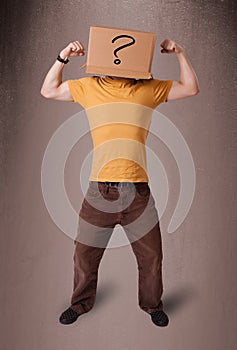 Young man gesturing with a cardboard box on his head with question mark