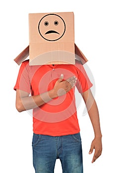 Young man gesturing with a cardboard box on his head with sad fa