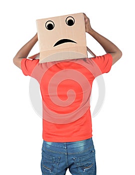 Young man gesturing with a cardboard box on his head with sad fa