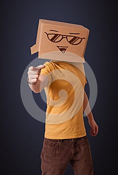 Young man gesturing with a cardboard box on his head with smiley