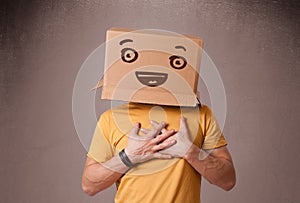 Young man gesturing with a cardboard box on his head with smiley